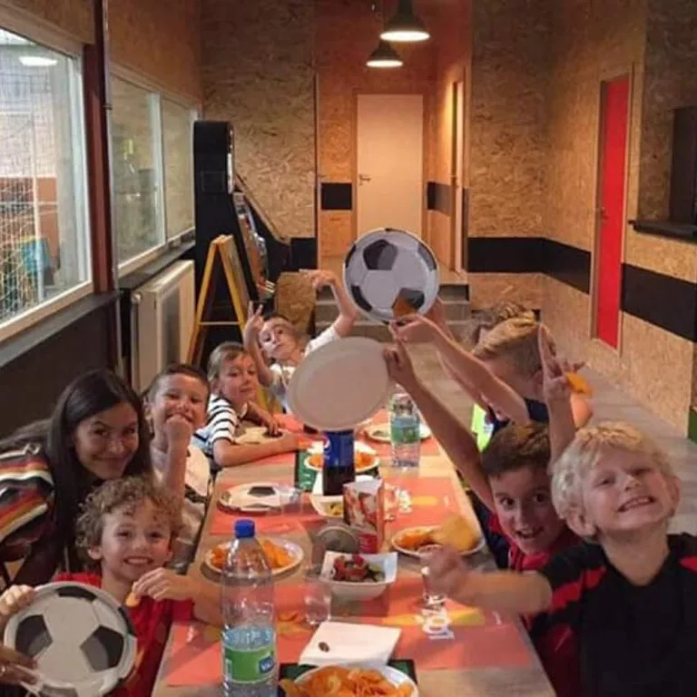 Een groep kinderen geniet van een heerlijke maaltijd tijdens een verjaardagsfeestje in Arena Gent Indoor Football